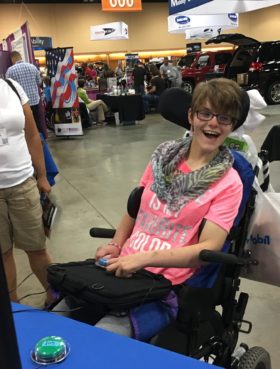 IMG_0786 A woman in a pink shirt, sitting in a wheelchair smiles as she figures out how to play video games